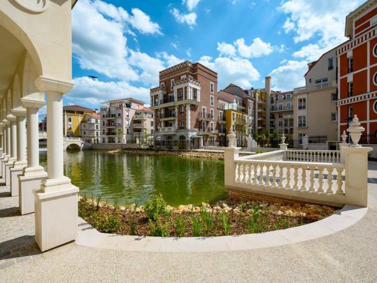 Livraison de Nouvelle Vague au Plessis-Robinson : façades inspirées de Venise, jardin paysager avec canal central et espaces de vie extérieurs.